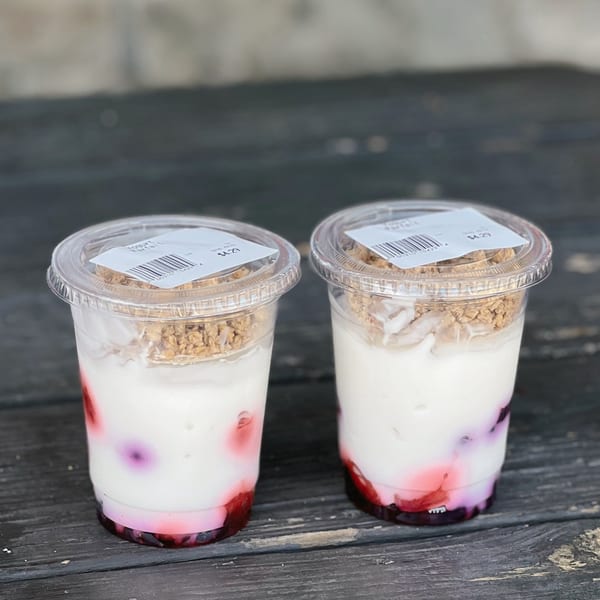 Two Country Corners Deli yogurt parfaits with berries and granola in clear plastic cups.