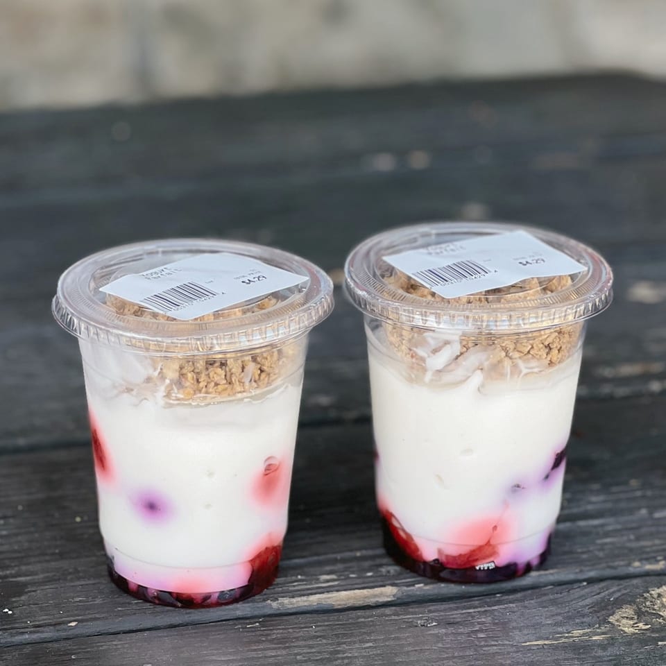 Two Country Corners Deli yogurt parfaits with berries and granola in clear plastic cups.