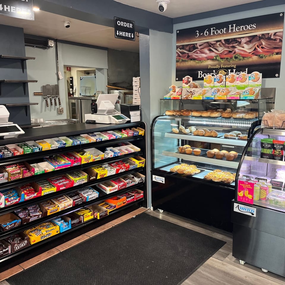Interior of Country Corners Deli, featuring a snack counter, bakery display, and sandwich sign.