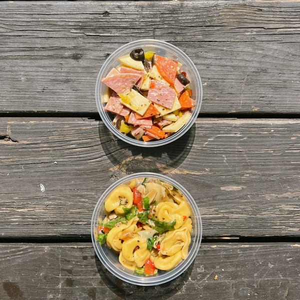 Two deli salads in clear plastic containers, one with tortellini, the other with meats and cheeses.