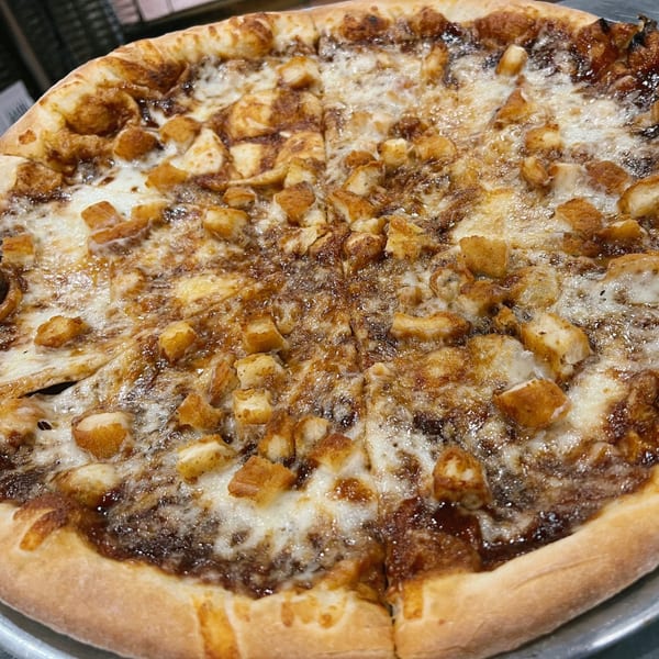 A Country Corners Deli pizza with a sweet sauce, melted cheese, and crispy chicken pieces.