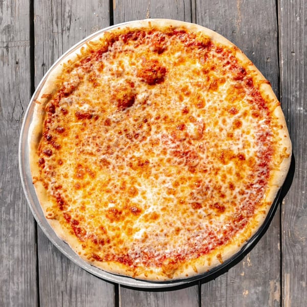 A whole cheese pizza with a golden crust on a metal tray, resting on a rustic wooden table.